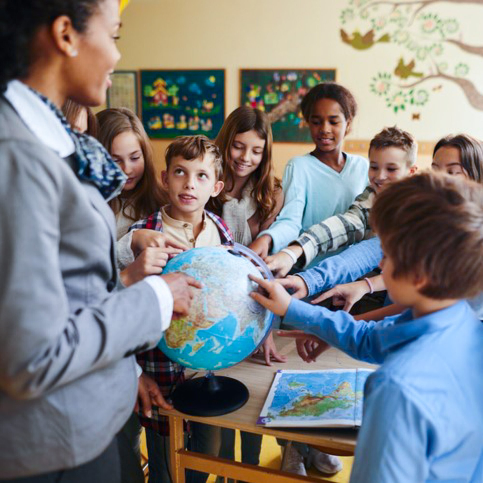 teacher and students pointing to different places on a globe