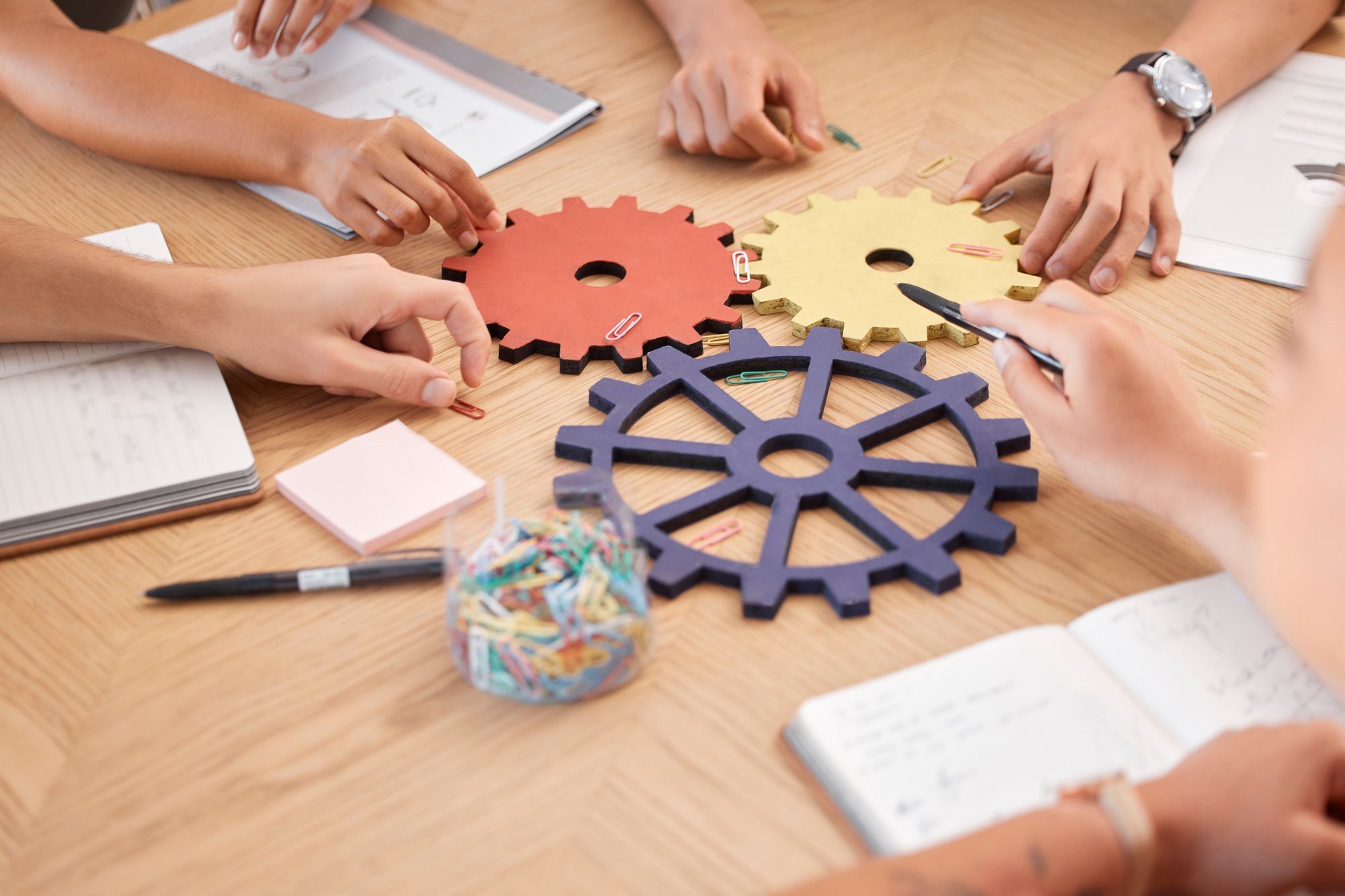 hands at a table around colorful gears