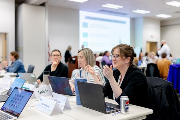 Three women at a table at a conference